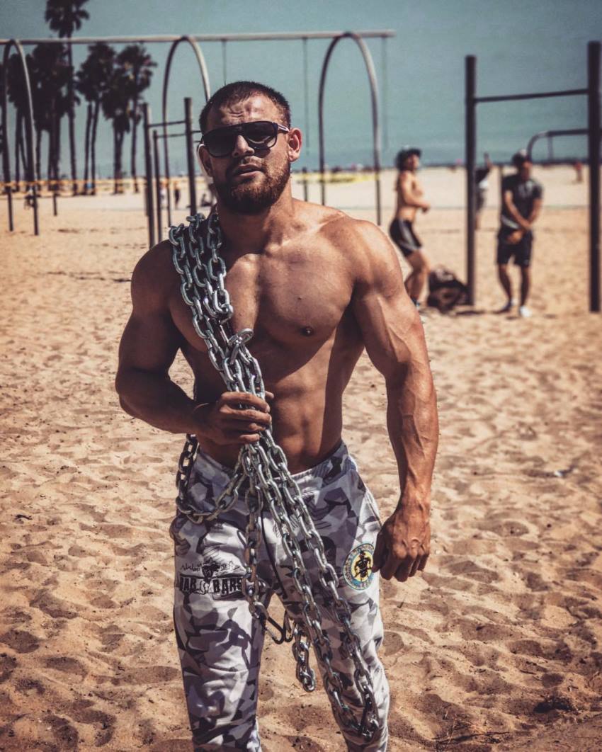 Islam Badurgov shirtless on the beach, having chains on his body