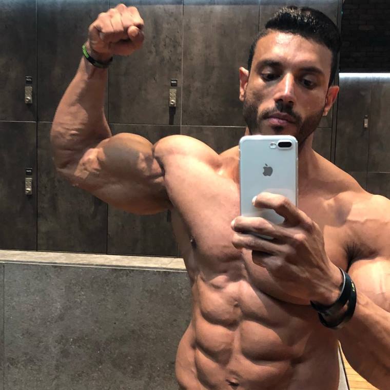 Hany Saeed taking a selfie of himself flexing his biceps and abs