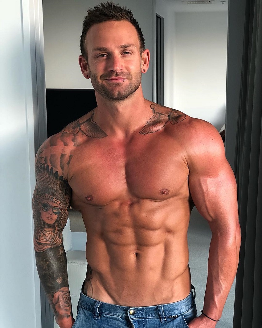 Joel Bushby posing shirtless for a photo looking strong and fit